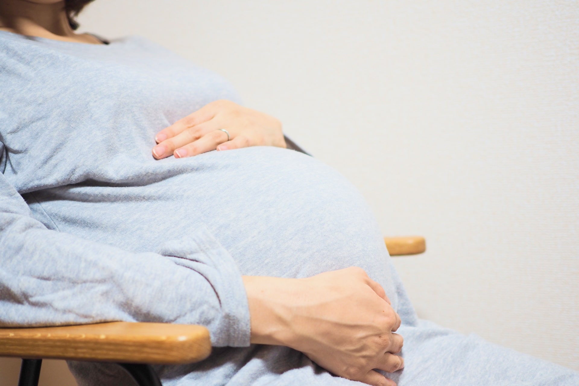 椅子に座りお腹を抱える妊婦さんの写真画像です。