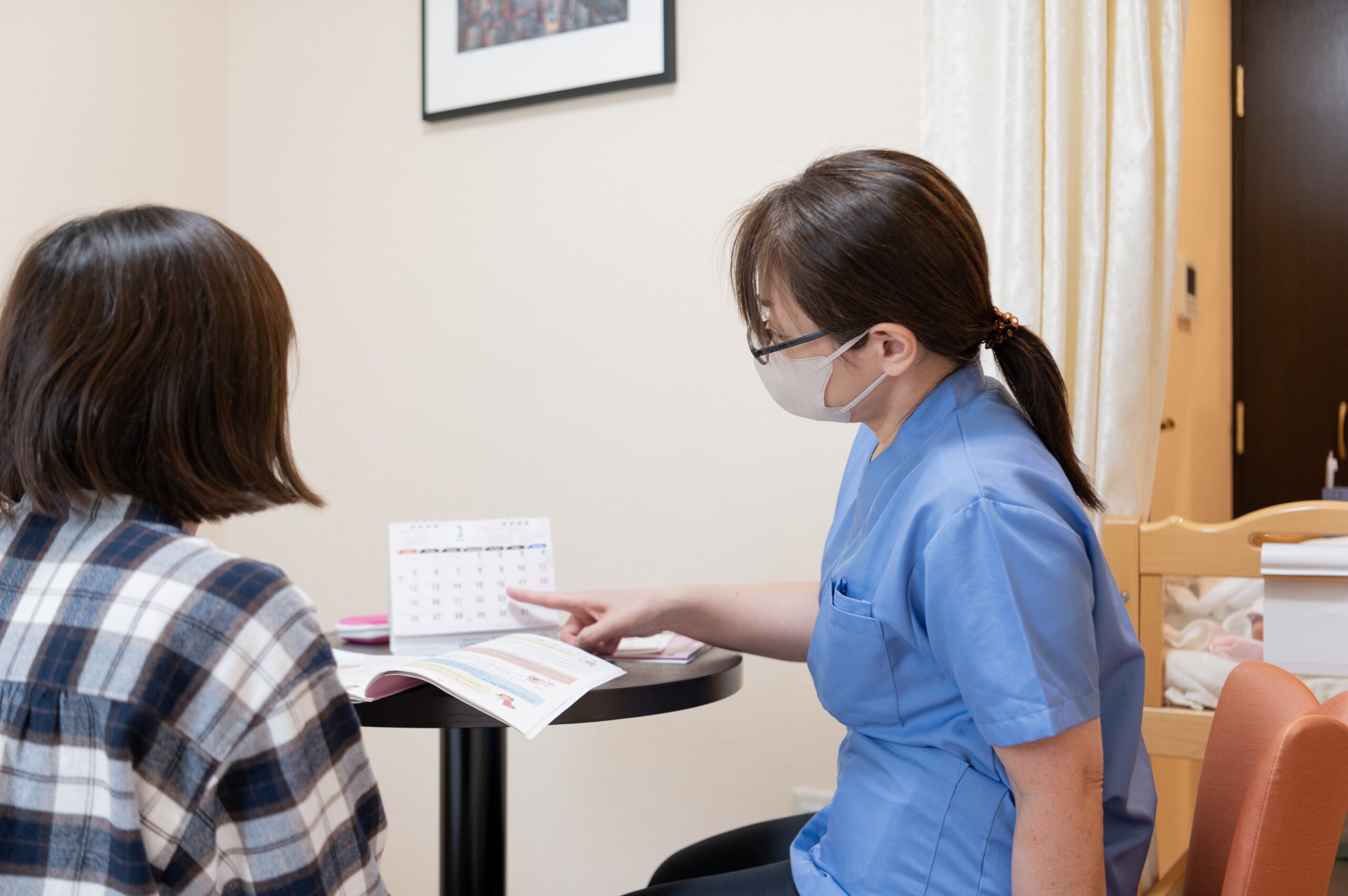 助産師外来で、妊婦さんと助産師がカレンダーを指しながら話をしている写真画像です。
