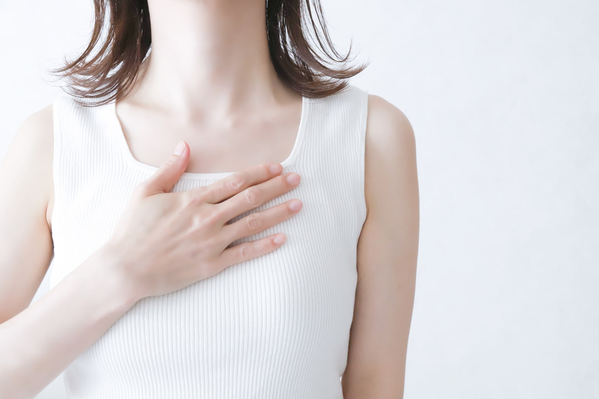 胸に手を当てている女性の写真です。