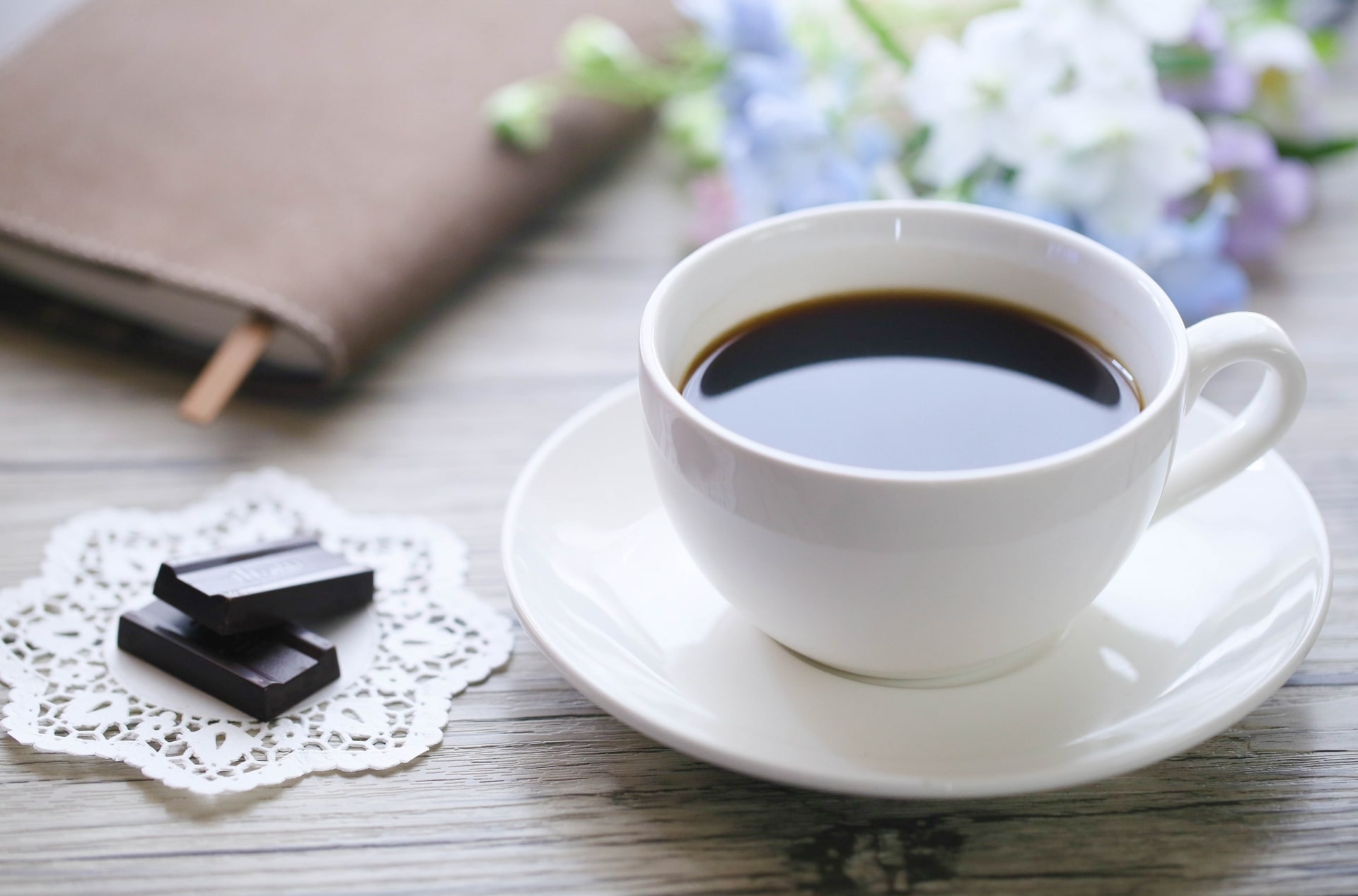 カップに入ったブラックコーヒーと、横に添えられたチョコレートの写真画像です。